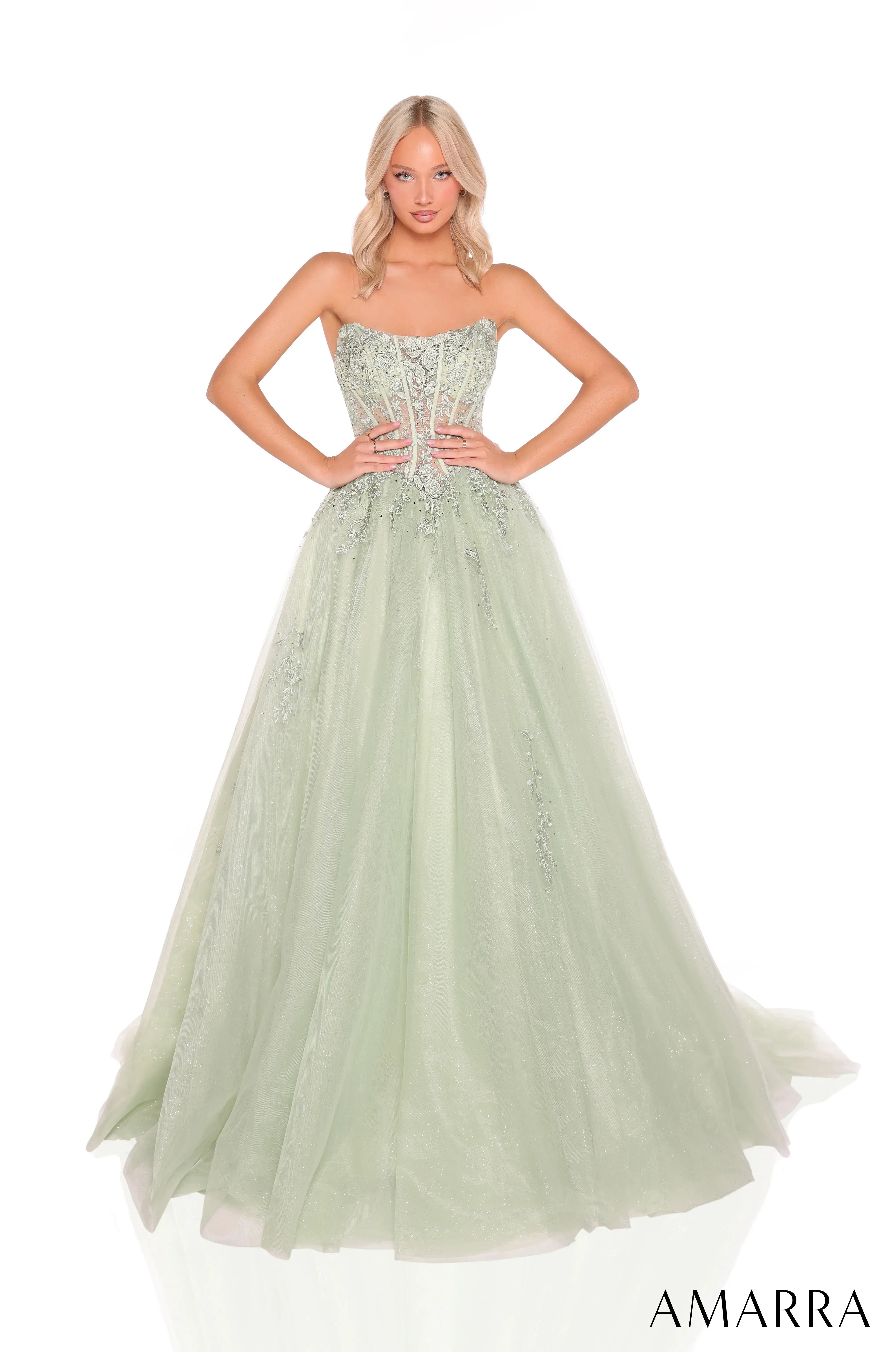 Woman wearing a light green evening gown with a strapless top and flowing skirt on a white background, brand 'AMARRA' visible.