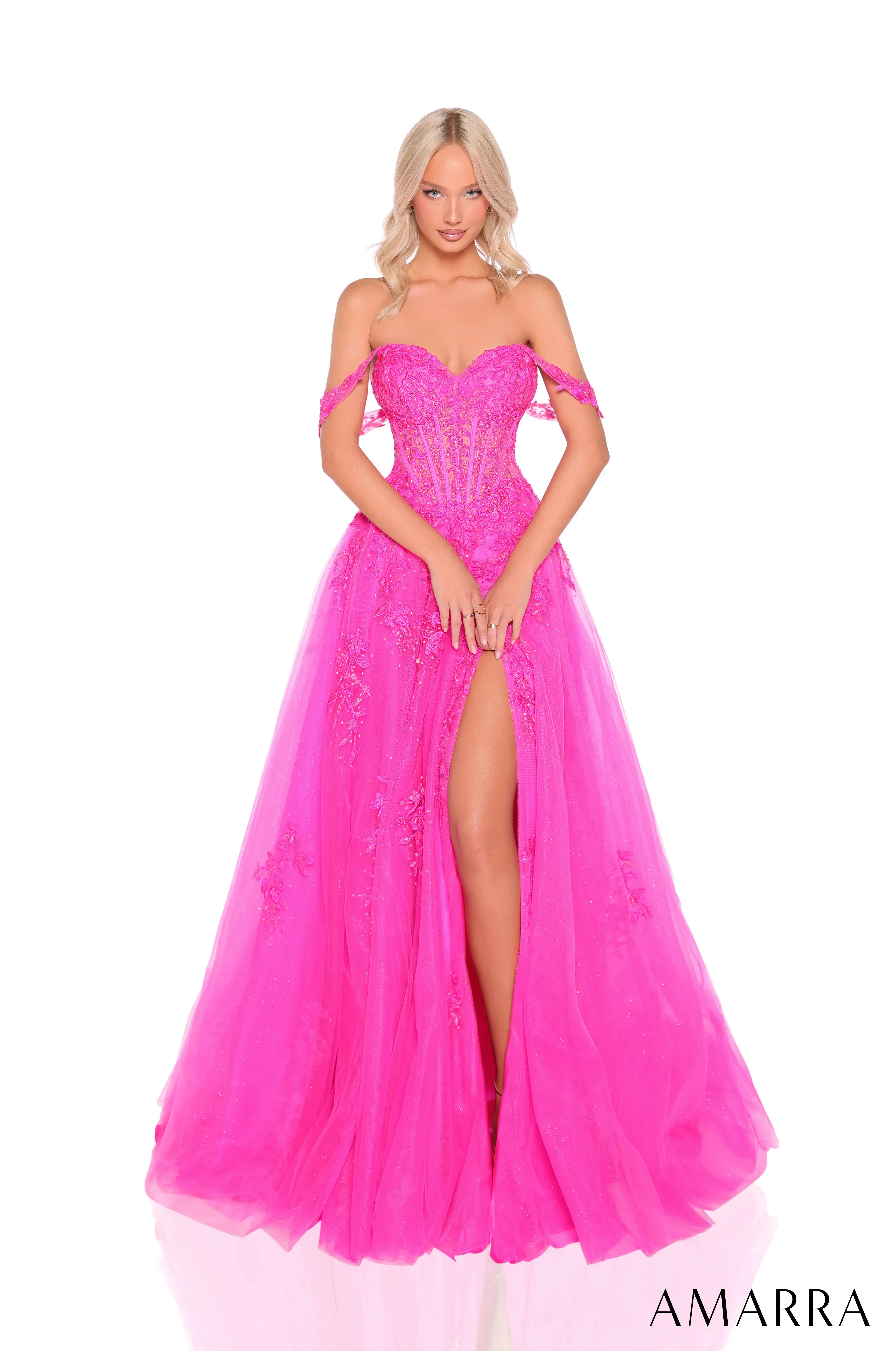 A blonde model wearing a bright hot pink off-the-shoulder ball gown with a sweetheart neckline, lace corset bodice, and a high thigh slit, shown against a plain white background with the AMARRA logo at the bottom right.