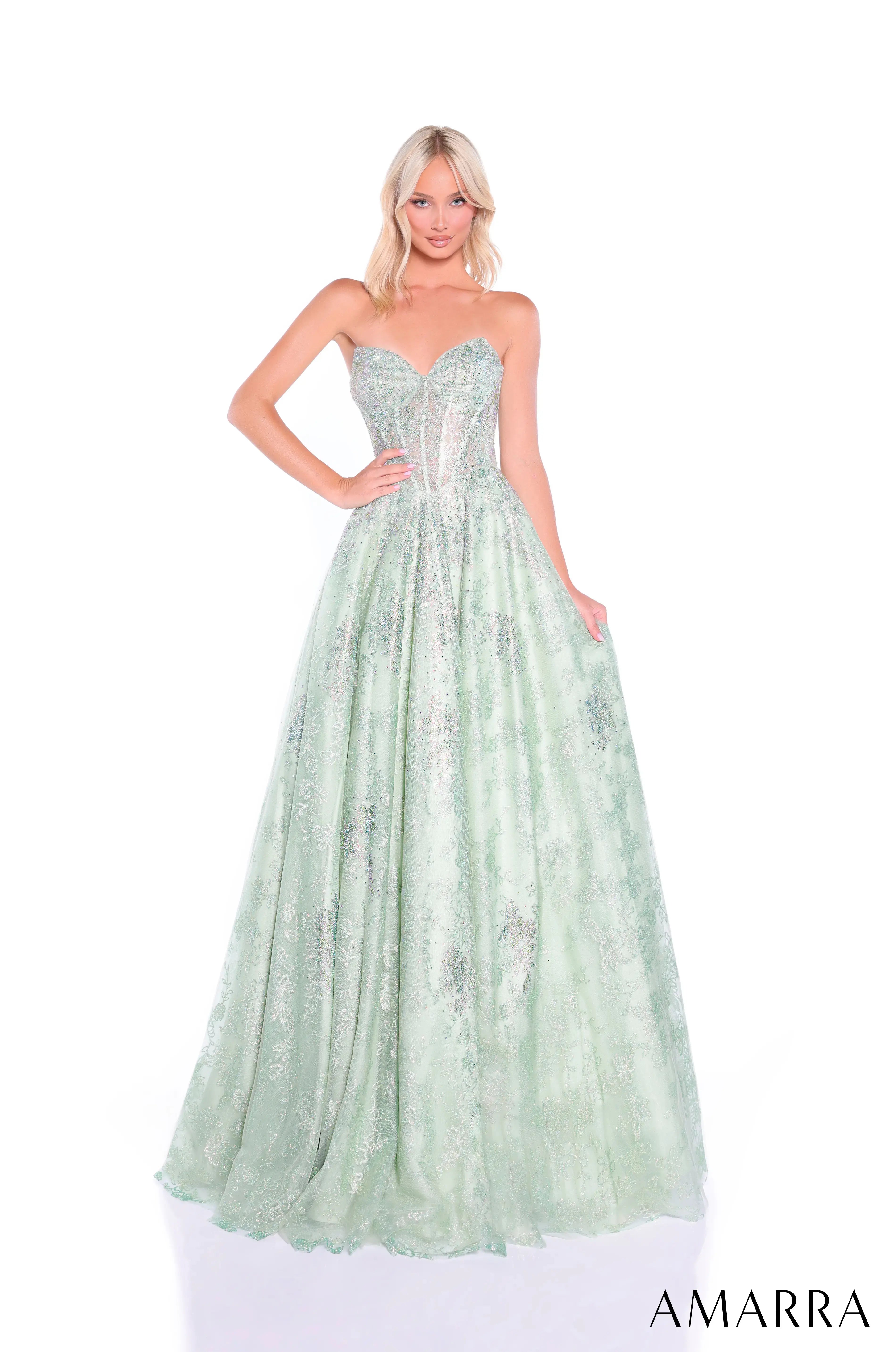 Woman wearing a light green evening gown with floral details on a white background, brand 'AMARRA' visible.