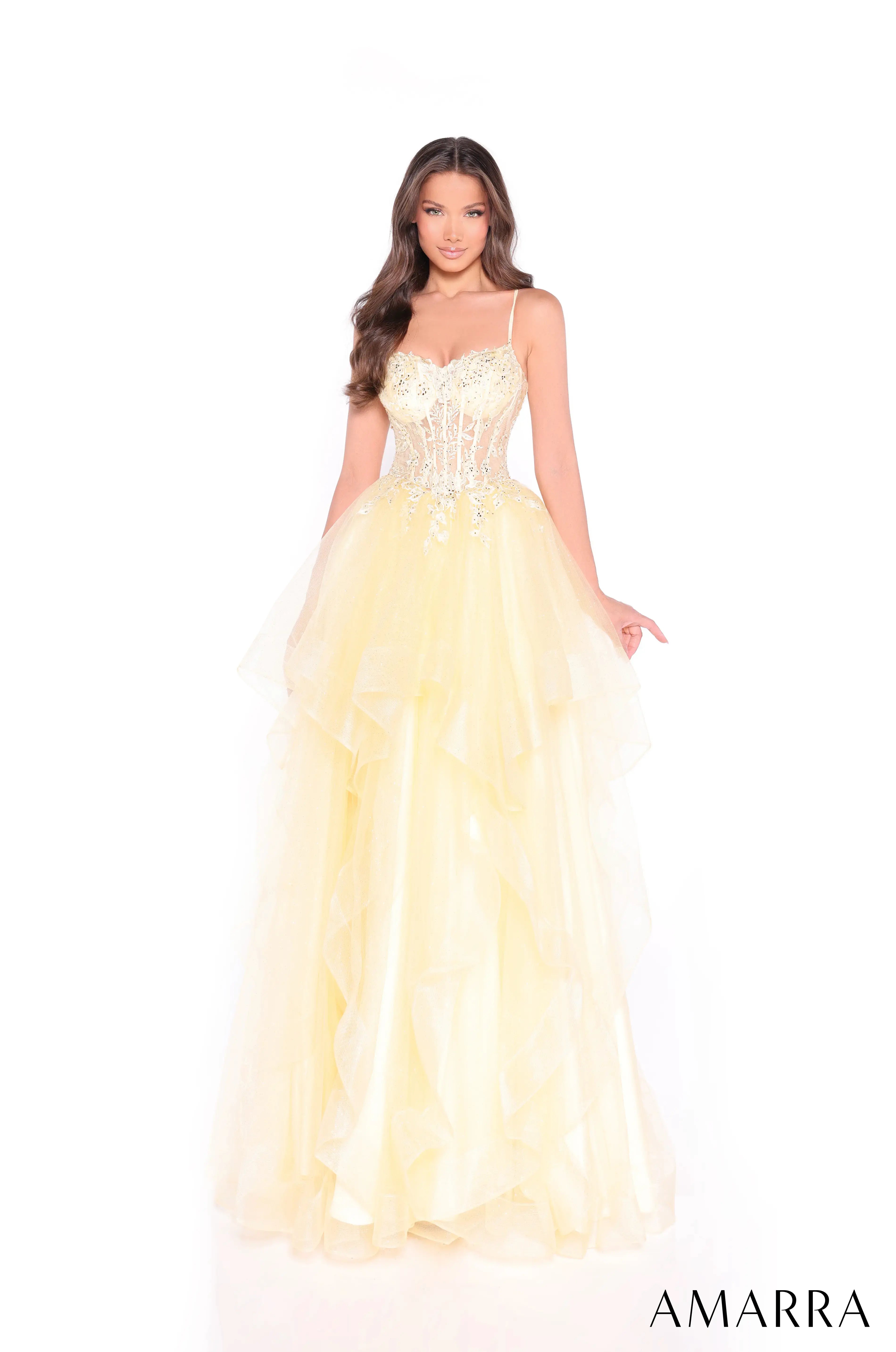 Woman wearing a yellow evening gown with floral details on a white background, brand 'AMARRA' visible.